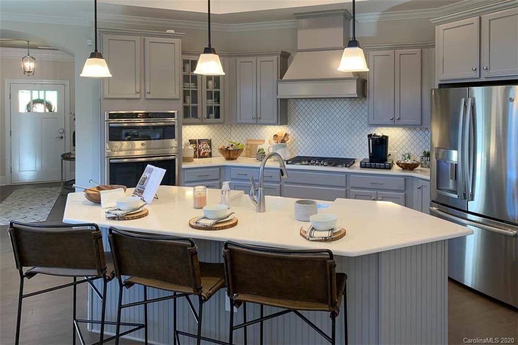 3002 Portico Place, Unit 38 Tega Cay, SC 29708 - Photo 16 of 38 a kitchen with stainless steel appliances kitchen island granite countertop a dining table and chairs