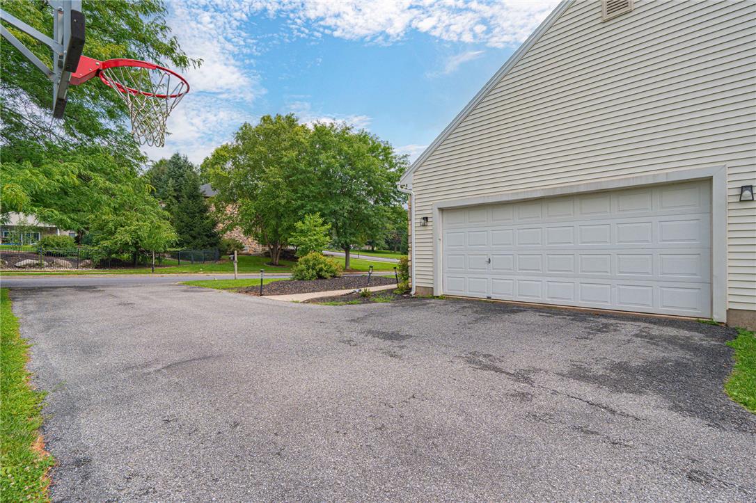 102 Sutton Road Easton, PA 18045 - Photo 8 of 83 An asphalt driveway leads to a multi-car garage beneath a vinyl-sided gable roof.
