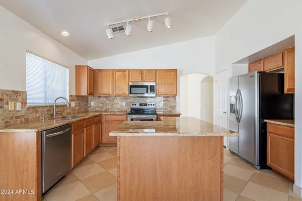 a modern kitchen with stainless steel appliances granite countertop a refrigerator a stove top oven a sink and dishwasher