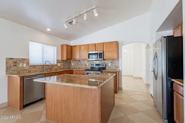a kitchen with stainless steel appliances granite countertop a sink stove refrigerator and cabinets