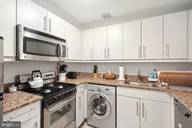 a kitchen with stainless steel appliances granite countertop white cabinets sink and dishwasher