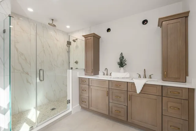 a bathroom with a double vanity sink mirror and shower
