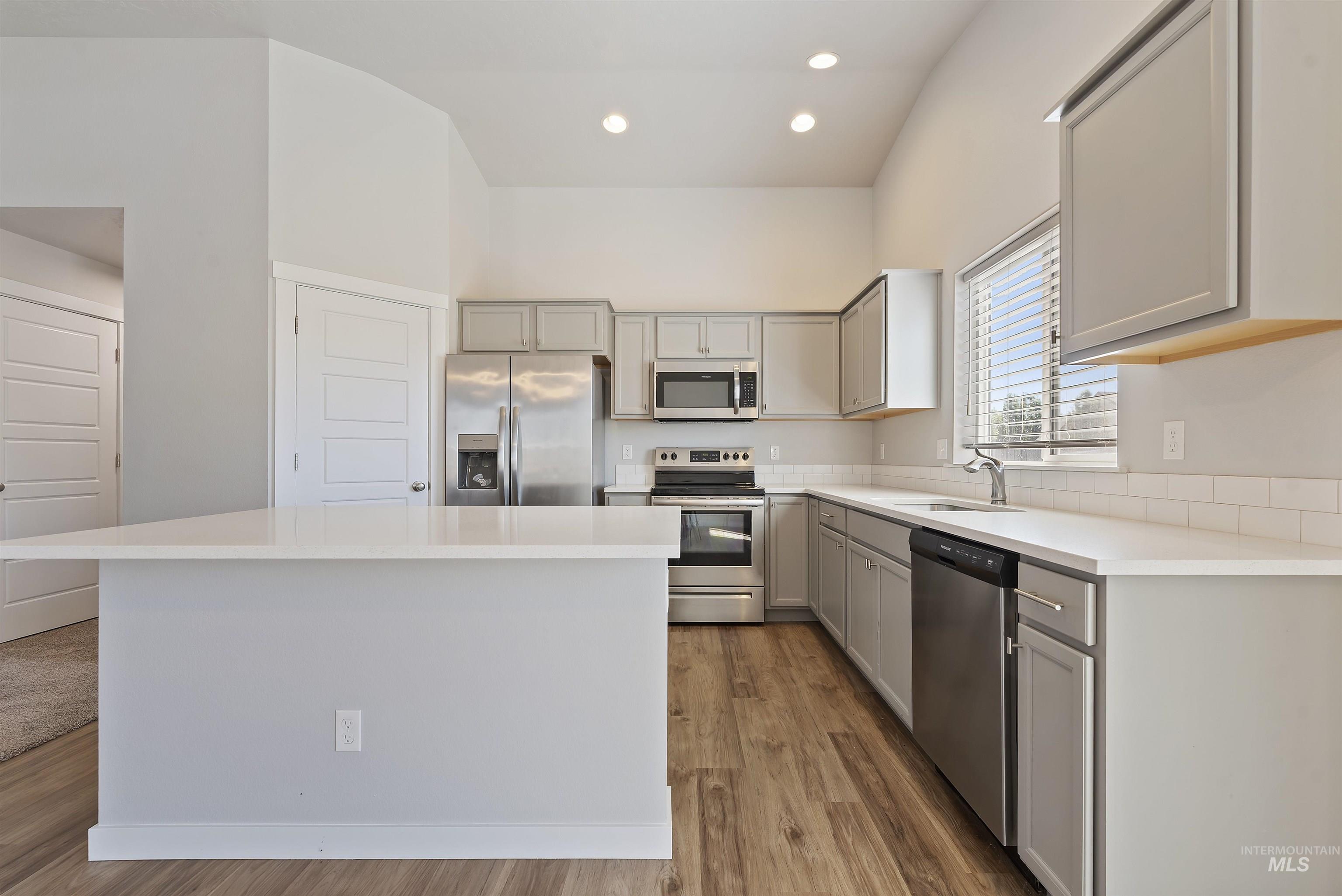 12703 West Fig Street Boise, ID 83713 - Photo 10 of 26 Kitchen featuring appliances with stainless steel finishes, gray cabinetry, recessed lighting, light wood-style floors, and a center island