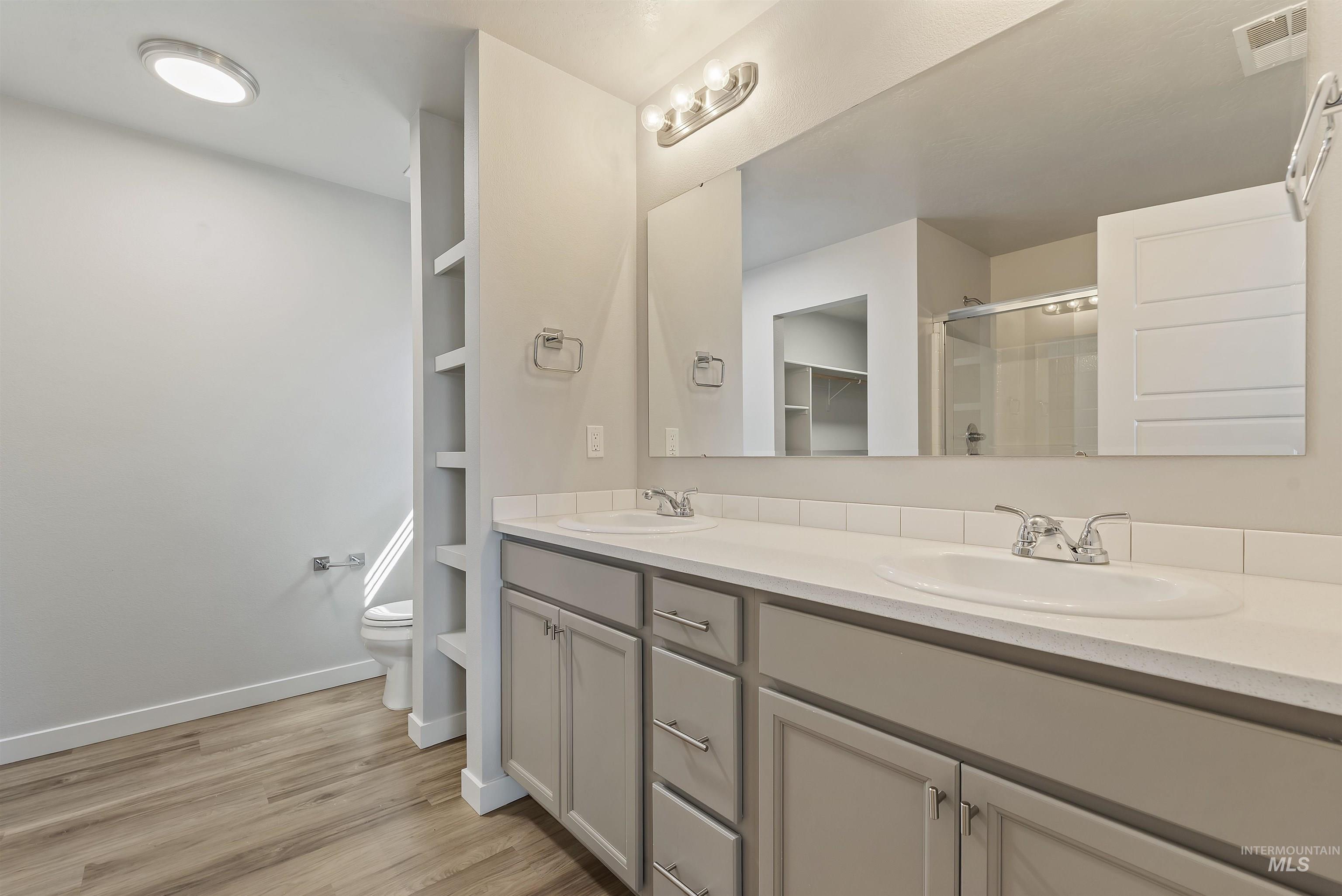12703 West Fig Street Boise, ID 83713 - Photo 17 of 26 Full bath featuring a stall shower, double vanity, light wood-style floors, and a spacious closet
