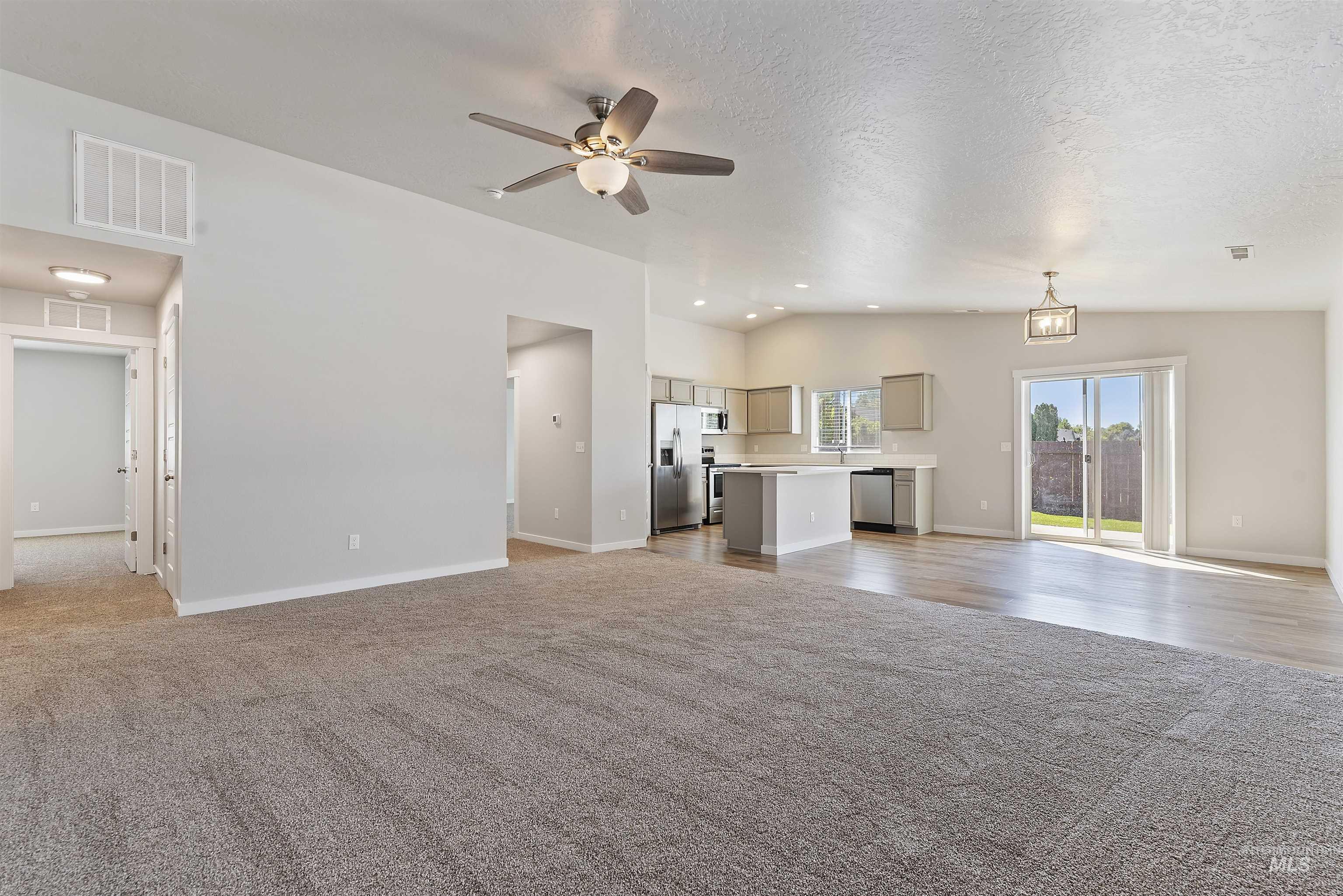 12703 West Fig Street Boise, ID 83713 - Photo 6 of 26 Unfurnished living room with light carpet, a ceiling fan, a textured ceiling, and lofted ceiling