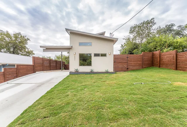 a backyard of a house with plants and wooden fence