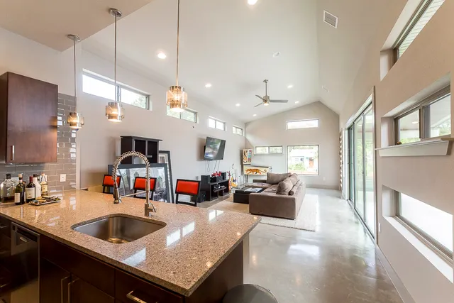 a kitchen with a sink a counter top space and living room view
