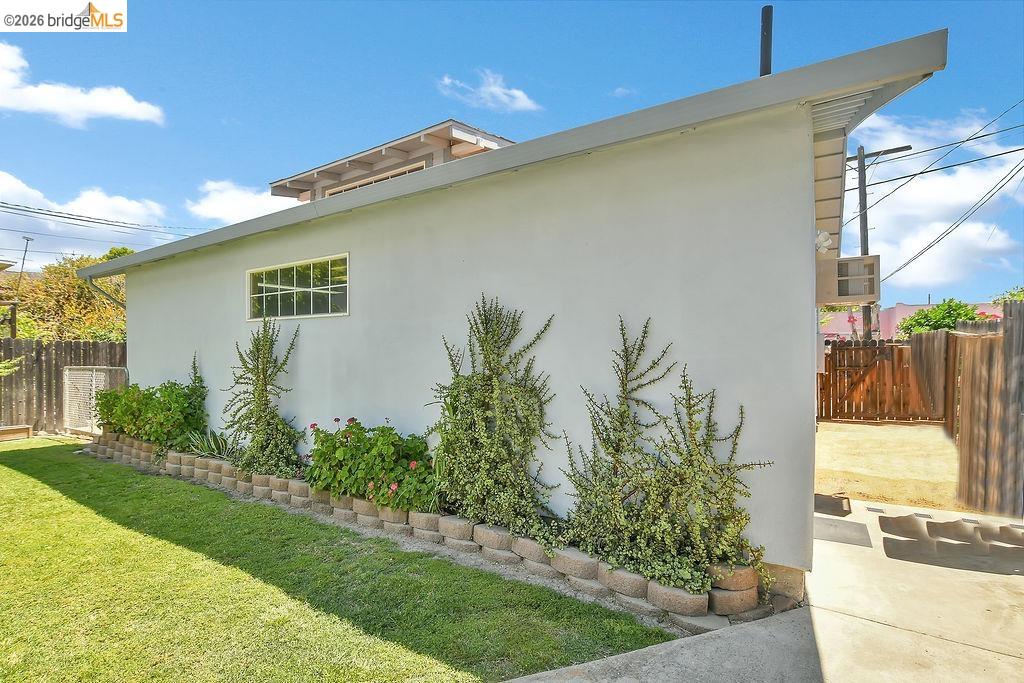 325 South 2nd Street Rio Vista, CA 94571 - Photo 25 of 33 Stucco exterior with a pitched roofline, featuring a horizontal grid window and concrete block retaining wall with mature plantings