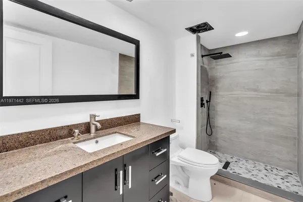 a bathroom with a granite countertop sink toilet and shower