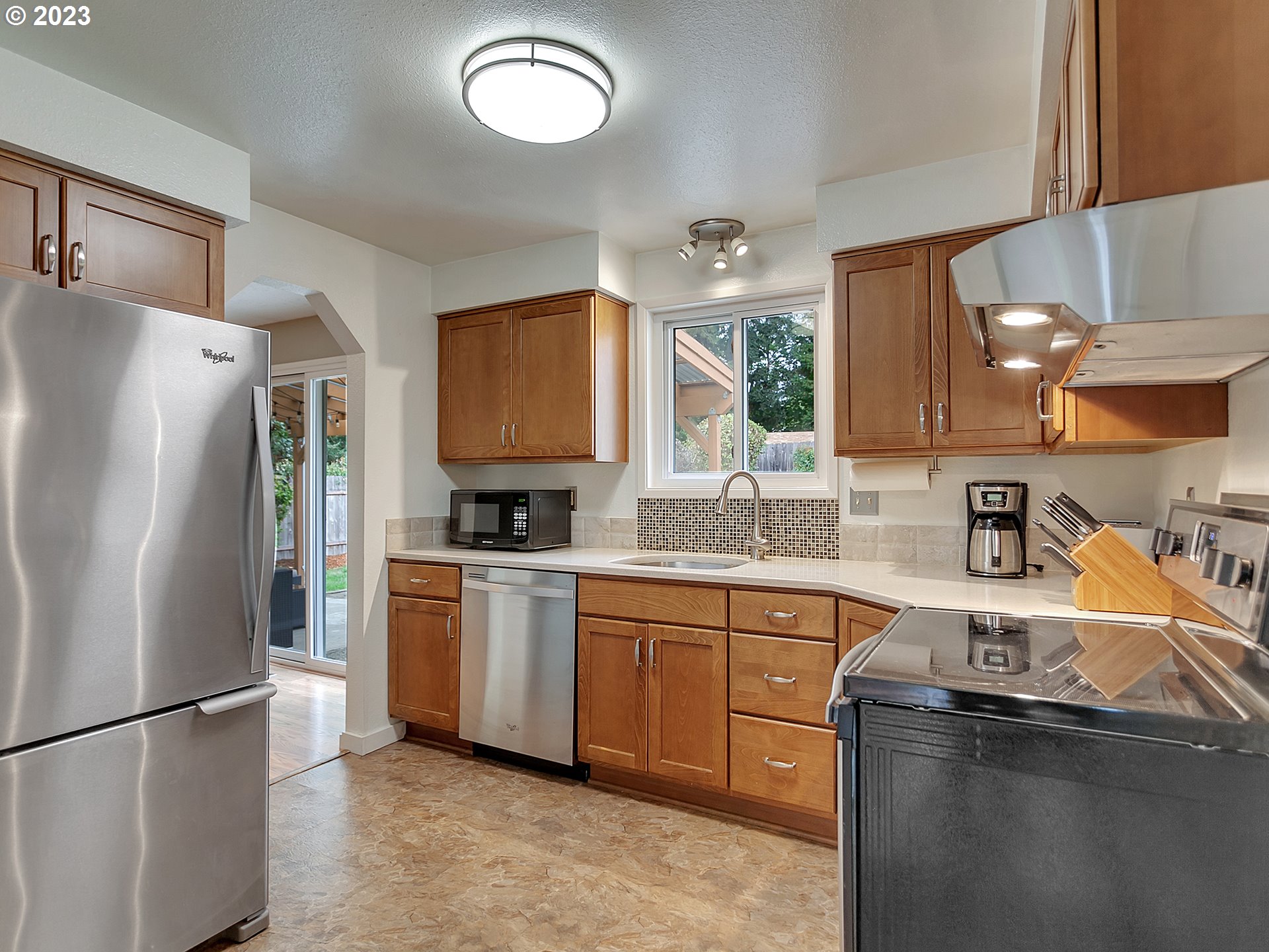 5715 Southwest Pendleton Street Portland, OR 97221 - Photo 8 of 31 a kitchen with stainless steel appliances granite countertop a refrigerator a sink dishwasher a stove with wooden cabinets and floor