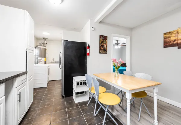 a kitchen with stainless steel appliances a dining table chairs and refrigerator