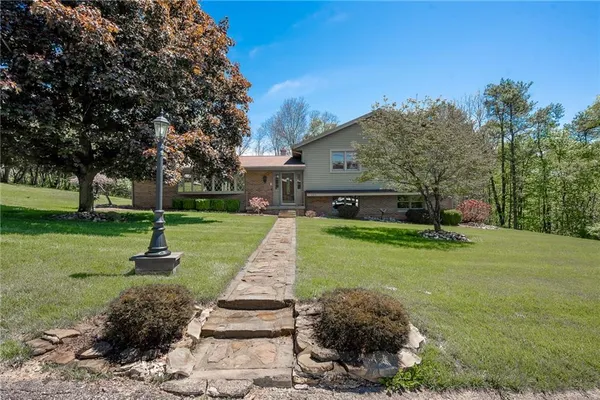 a front view of a house with a yard tree and green space