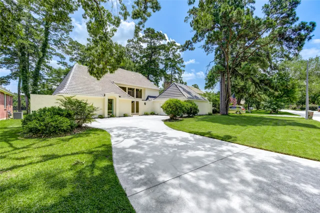a view of a house with a big yard plants and large trees