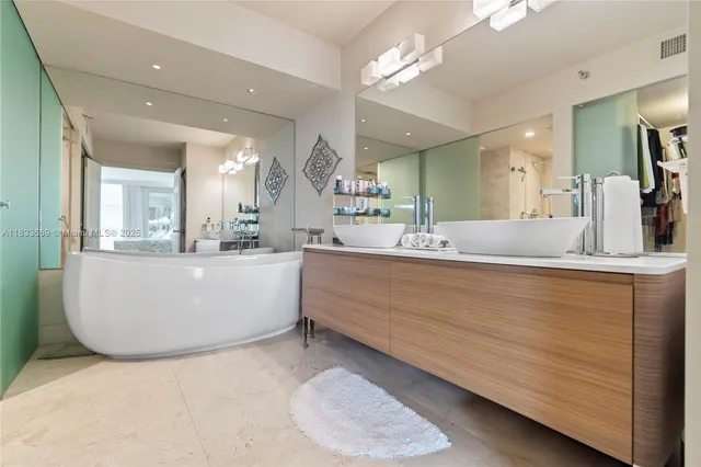a bathroom with a tub double sink and glass door