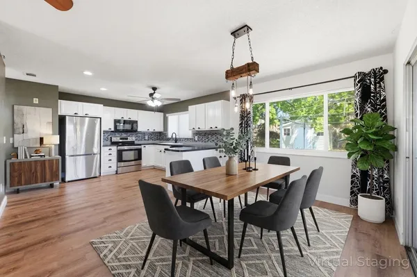 a kitchen with stainless steel appliances granite countertop a refrigerator a sink dishwasher a stove with white cabinets and wooden floor