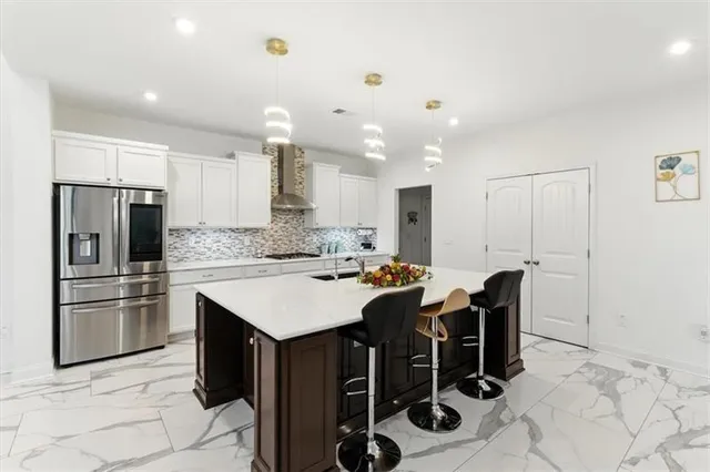 a kitchen with stainless steel appliances kitchen island granite countertop a sink a stove a refrigerator and island with wooden floor