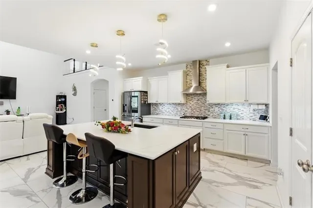 a kitchen with stainless steel appliances kitchen island granite countertop a table chairs sink and cabinets