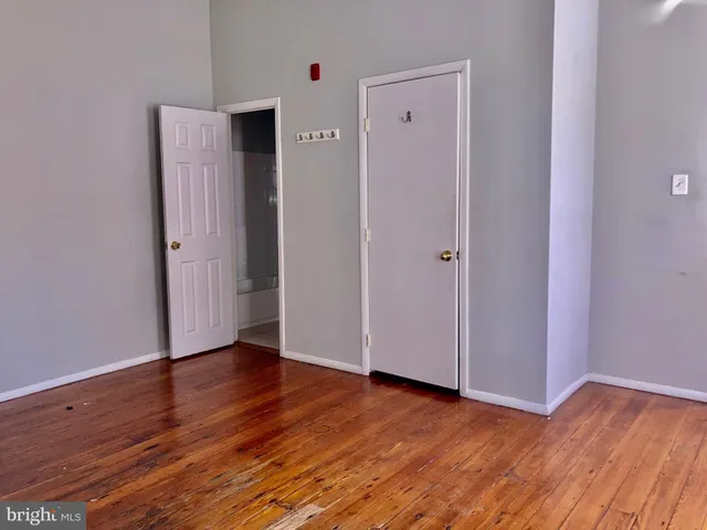 a view of an empty room with wooden floor and closet