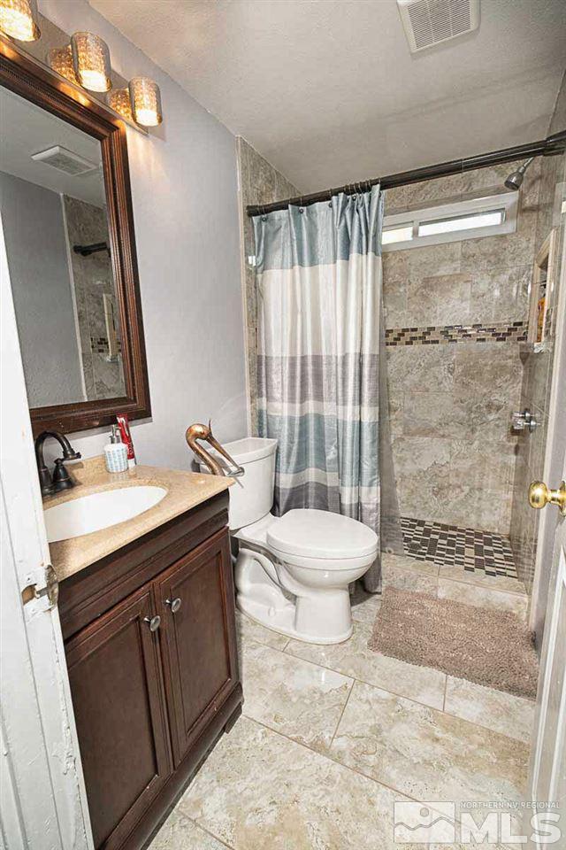 2745 Snapdragon Way Reno, NV 89512 - Photo 16 of 30 a bathroom with a granite countertop sink toilet a mirror and shower