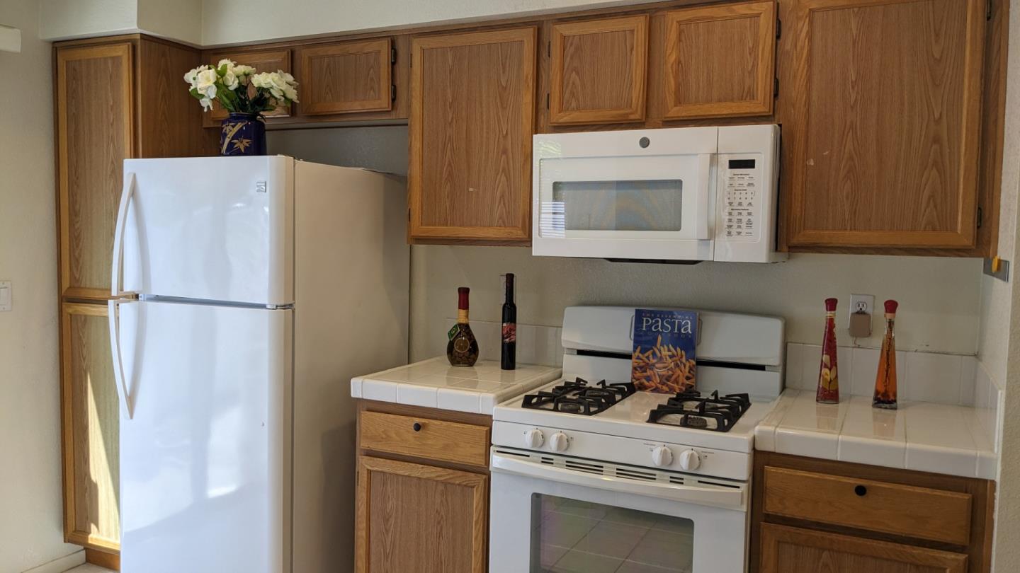 5691 Spry Common Fremont, CA 94538 - Photo 11 of 20 a kitchen with refrigerator a stove a sink and cabinets