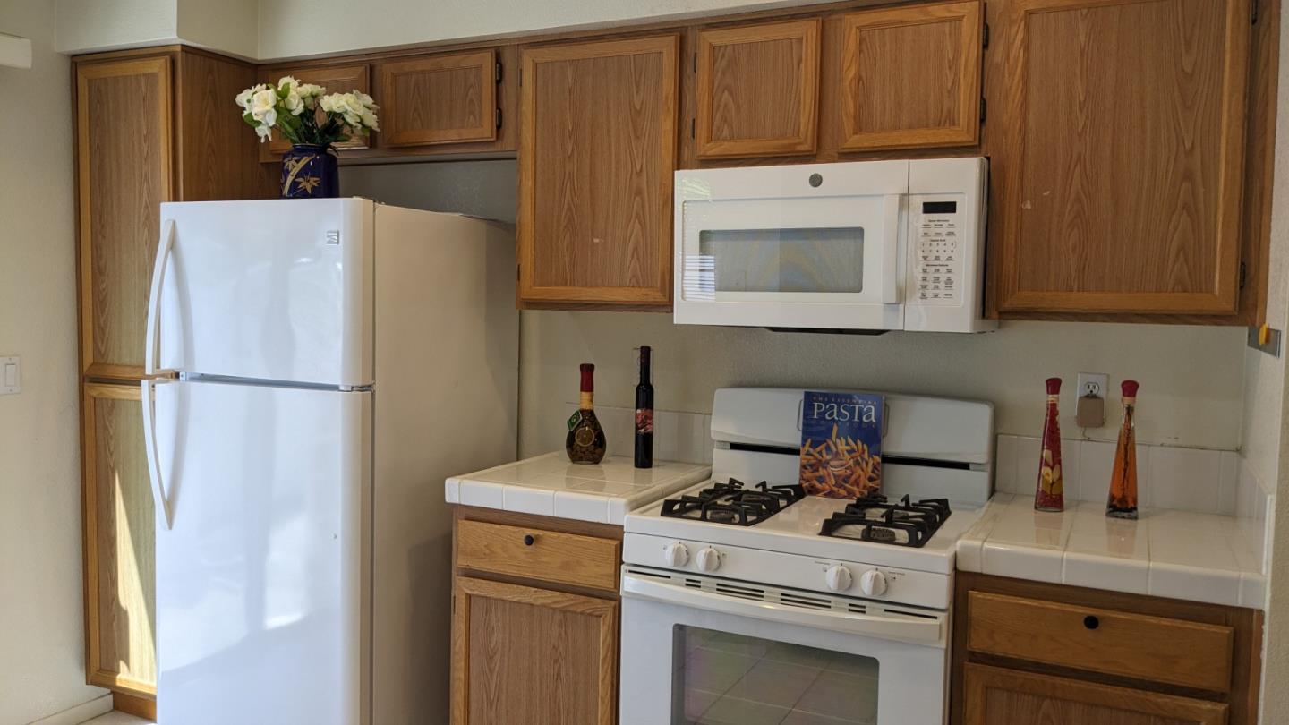 5691 Spry Common Fremont, CA 94538 - Photo 8 of 20 a kitchen with a stove a refrigerator and cabinets