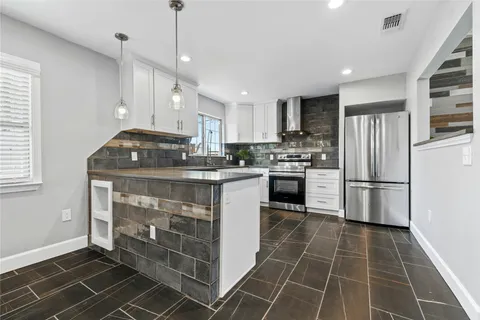 a kitchen with kitchen island a counter top space a sink cabinets and stainless steel appliances