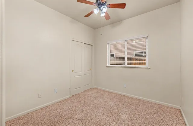 an empty room with a window and a ceiling fan