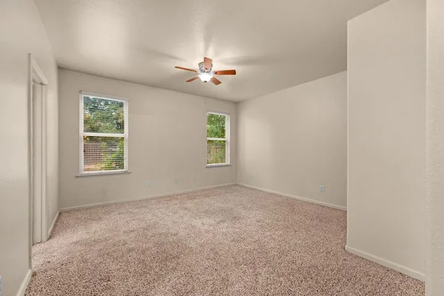 an empty room with windows and ceiling fan