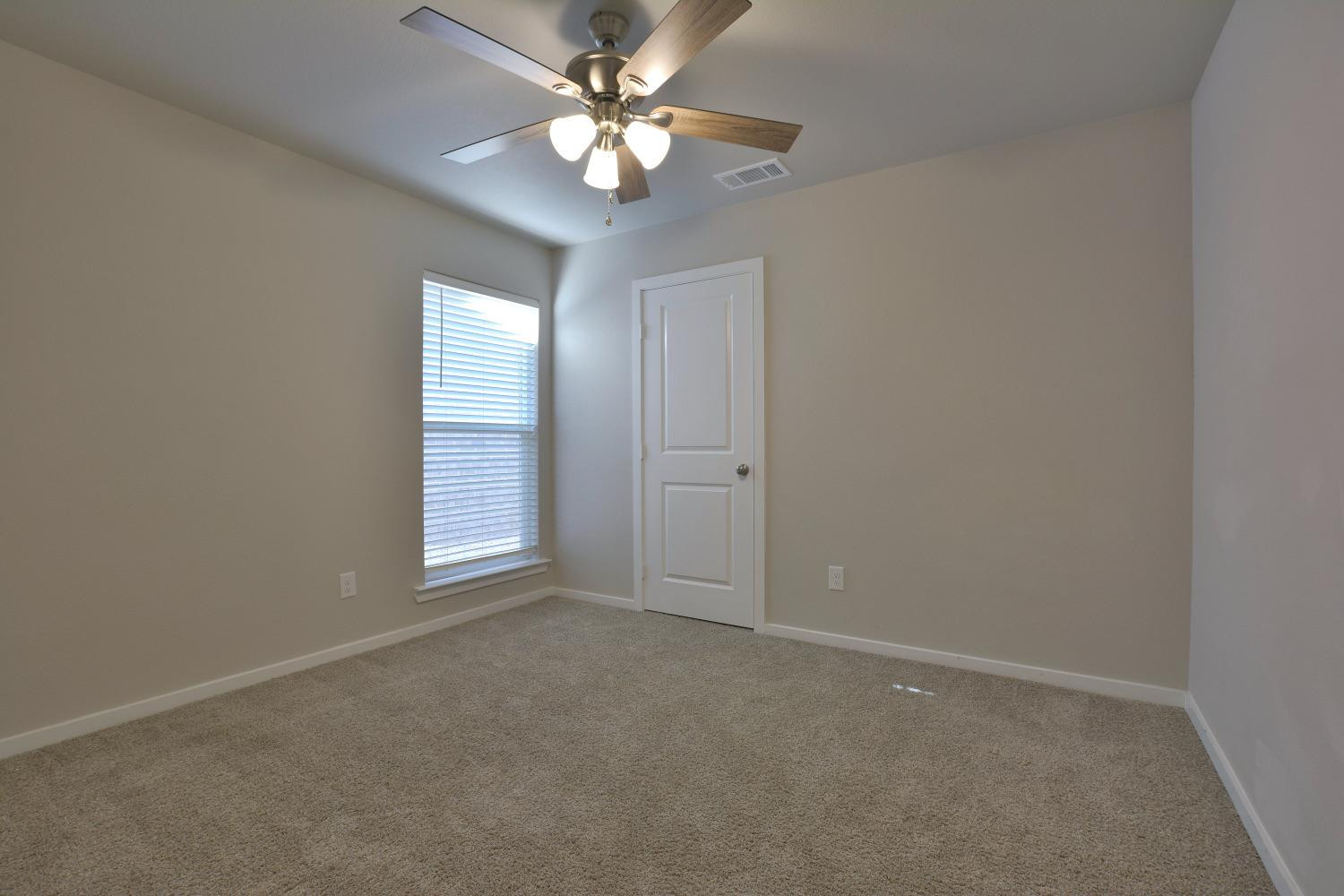 7513 28th Street Lubbock, TX 79407 - Photo 16 of 18 an empty room with a chandelier fan and windows