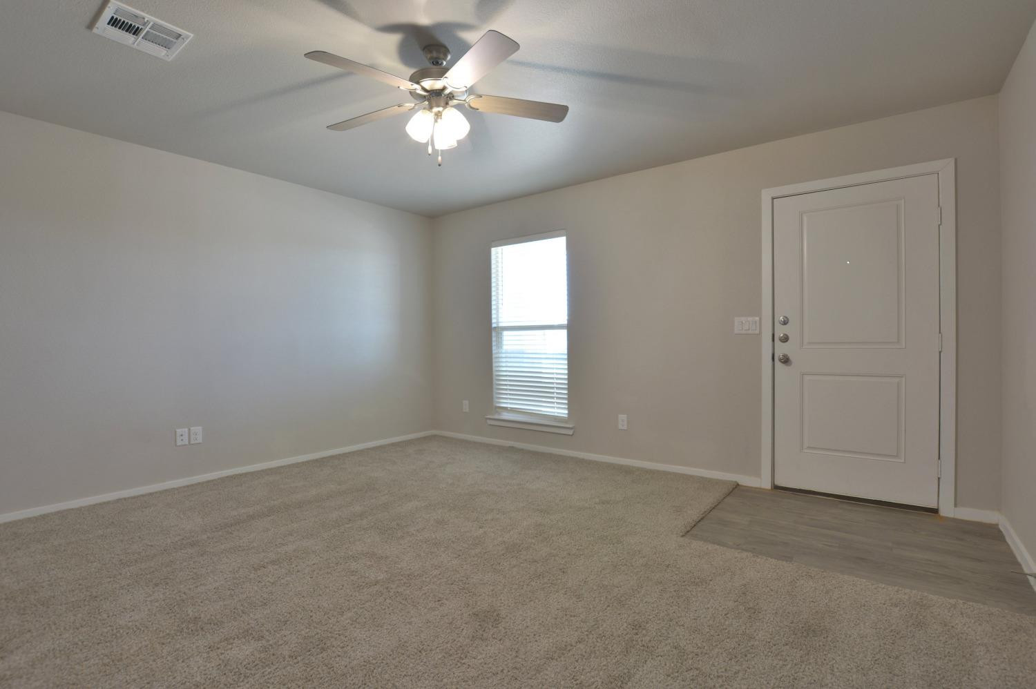 7513 28th Street Lubbock, TX 79407 - Photo 5 of 18 an empty room with a chandelier fan and windows