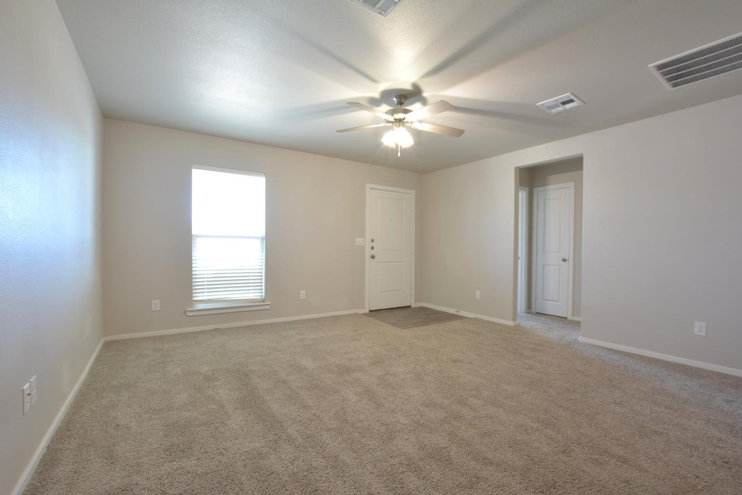 7513 28th Street Lubbock, TX 79407 - Photo 6 of 18 an empty room with chandelier fan and windows