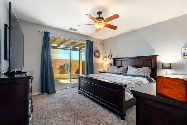 a bedroom with a bed and a flat tv screen on dresser