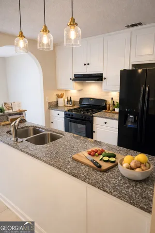 a kitchen with granite countertop a sink a stove and refrigerator