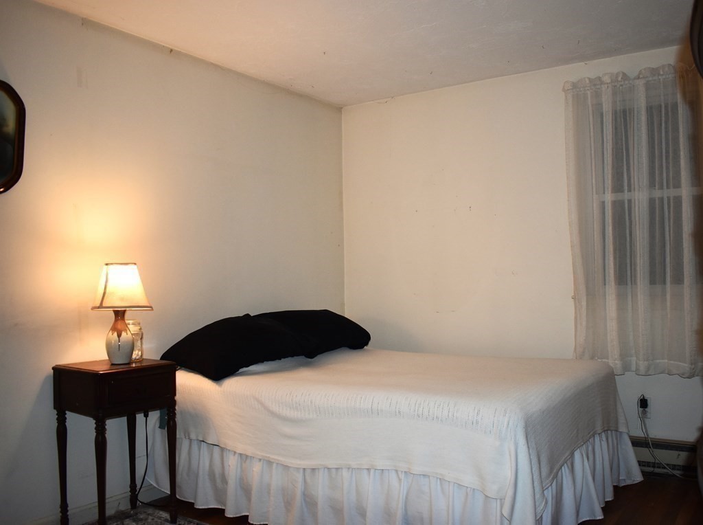 1702 State Road Plymouth, MA 02360 - Photo 12 of 17 a bedroom with a bed a lamp and a window