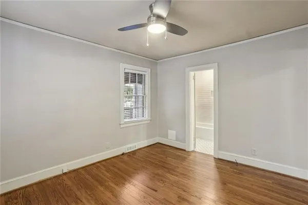 an empty room with wooden floor chandelier fan and windows