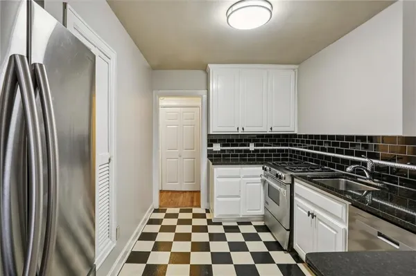 a kitchen with a refrigerator a sink and white cabinets