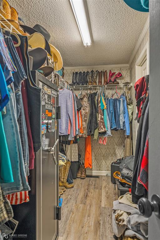 8273 Godfrey Road Shreveport, LA 71129 - Photo 22 of 27 Walk-in closet featuring wood-finish flooring, built-in wire shelving, and overhead fluorescent lighting