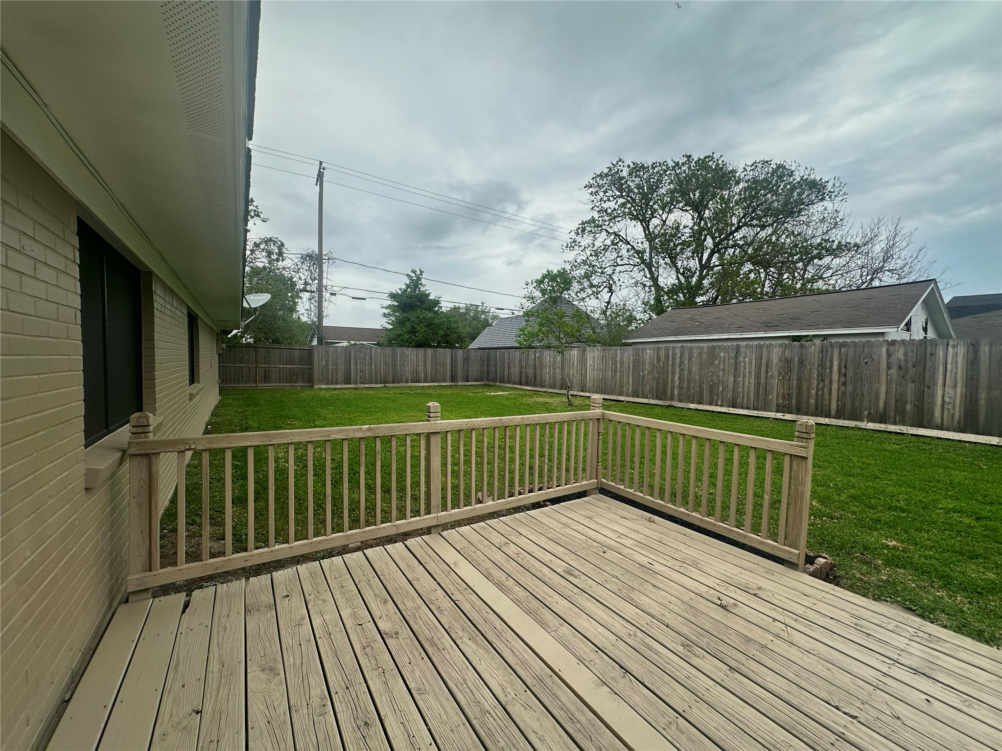 130 Bay Ridge Drive Baytown, TX 77523 - Photo 16 of 20 A spacious backyard features a wooden deck ideal for outdoor activities, surrounded by a privacy fence. The lawn is well-maintained, offering a great space for relaxation and entertainment.