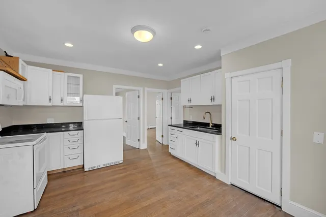 a kitchen with granite countertop white cabinets and white appliances