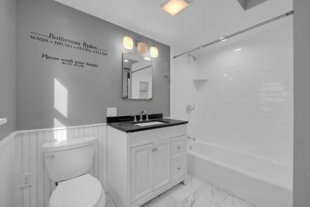a bathroom with a granite countertop sink a toilet a mirror and shower