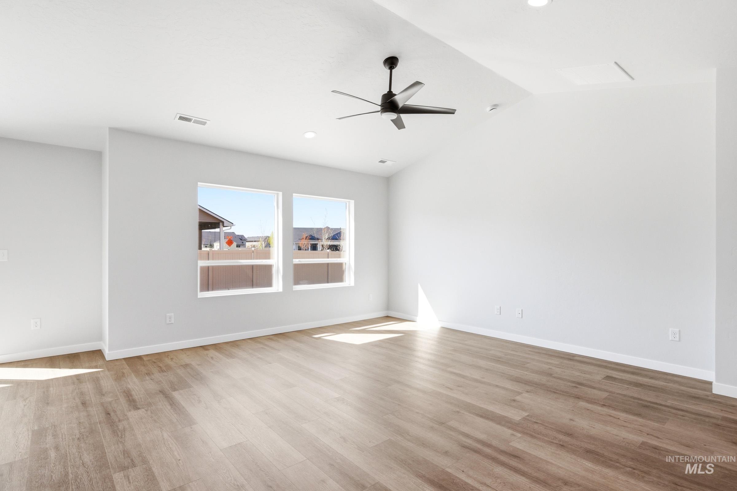 12877 Decatur Street Nampa, ID 83651 - Photo 12 of 22 Spacious interior room featuring light wood-finish flooring, two large windows, a ceiling fan, recessed lighting, and white baseboards