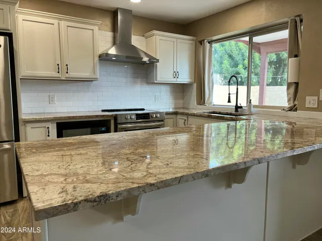 a kitchen with stainless steel appliances granite countertop a sink a stove and cabinets
