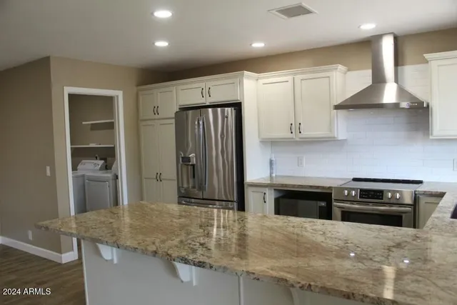 a kitchen with stainless steel appliances granite countertop a stove a sink and a refrigerator