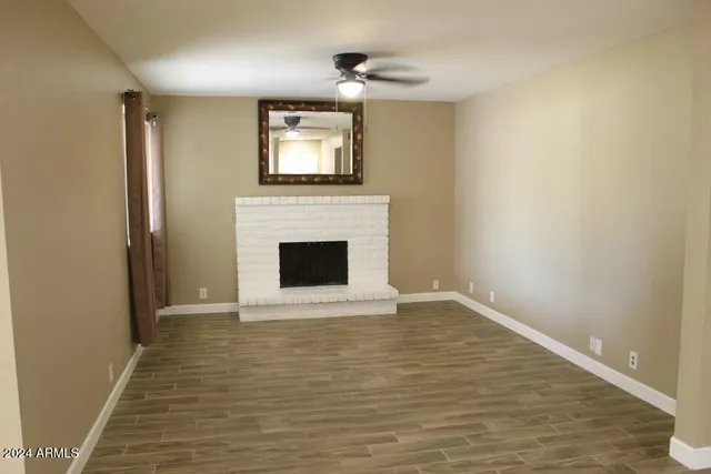 a view of empty room with wooden floor and fireplace