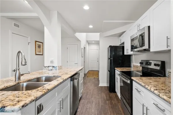 a kitchen with kitchen island granite countertop a sink stove and refrigerator