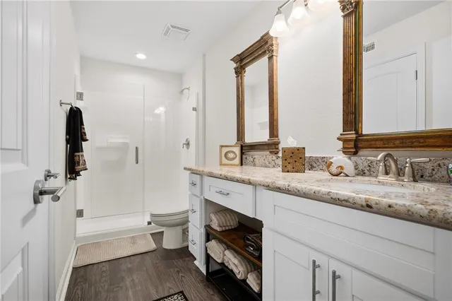 a spacious bathroom with a granite countertop sink a toilet a mirror and shower