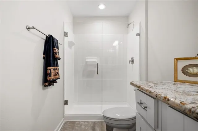 a bathroom with a granite countertop sink a toilet and shower