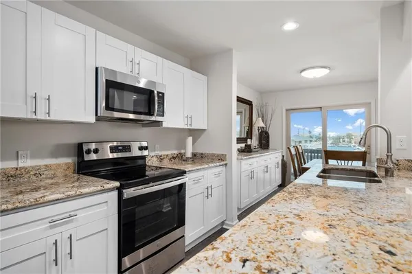 a kitchen with granite countertop a stove a sink and a microwave