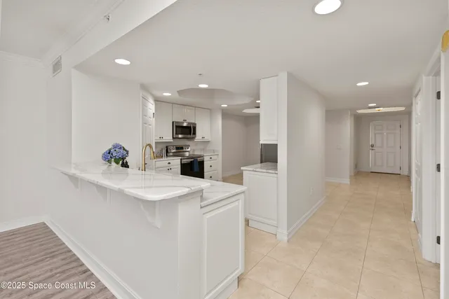 a kitchen with stainless steel appliances kitchen island granite countertop a sink and a refrigerator