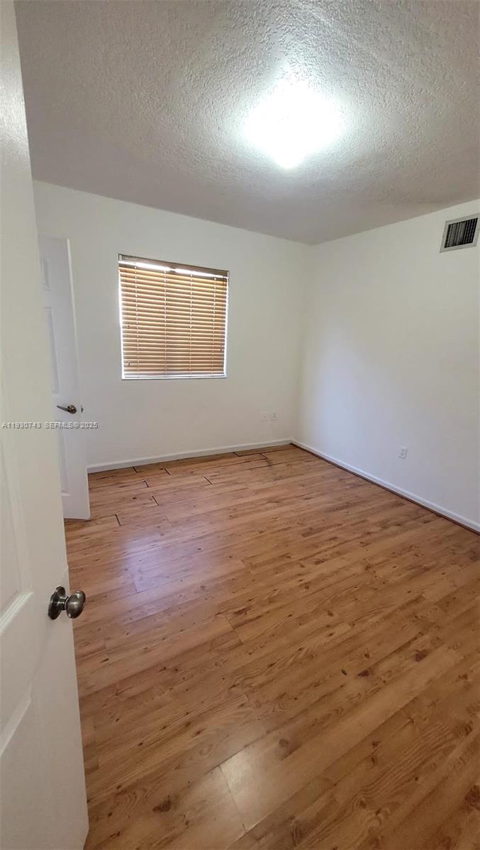 7241 Northwest 174th Terrace, Unit 103 Hialeah, FL 33015 - Photo 18 of 19 an empty room with wooden floor and windows